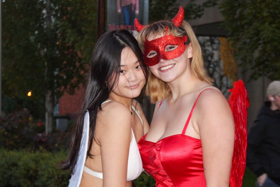 Two students dressed as an angel and a devil pose for a picture on campus.