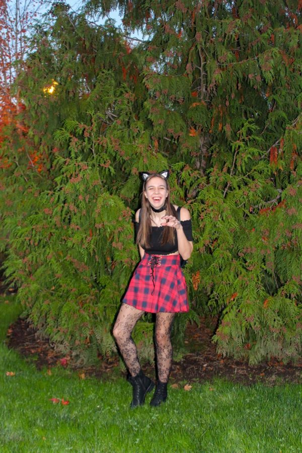 A student dressed as a cat poses Lin front of a tree.