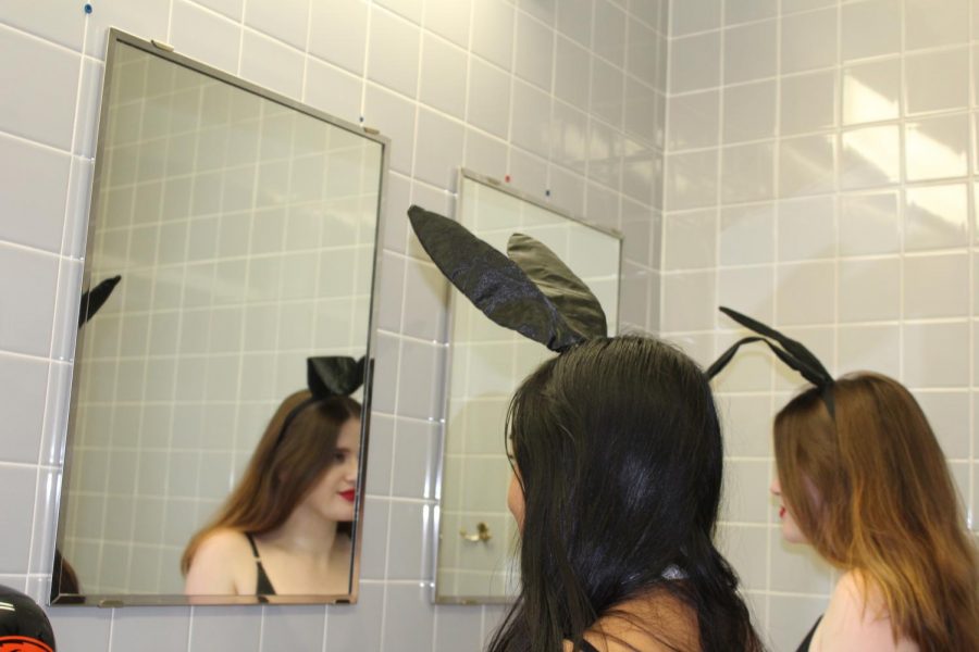 Two OSU students dressed as Playboy Bunnies look at themselves in a mirror.