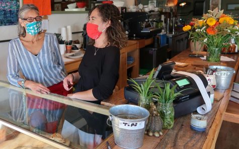 Two baristas laughing as they take orders