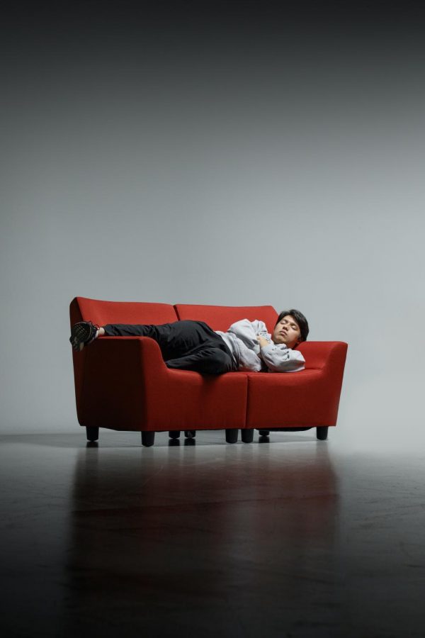 A person naps on a couch in a dark, empty room.