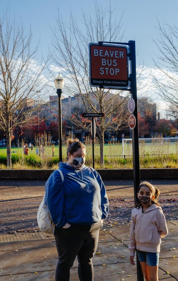 OSU Alumna Thannia Williams waits for the Beaver Bus with her young daughter.