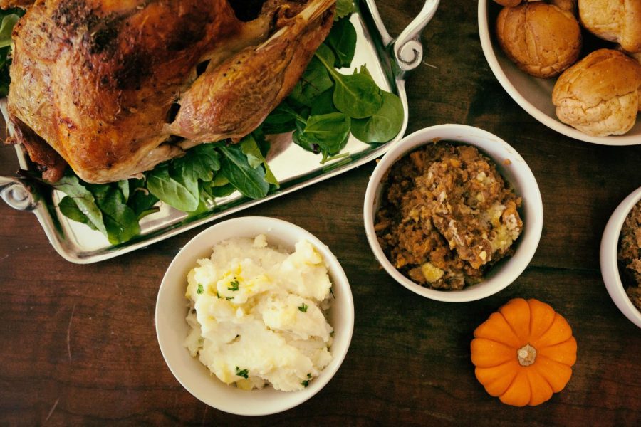 A Thanksgiving meal consisting of a turkey, mashed potatoes, stuffing and rolls.