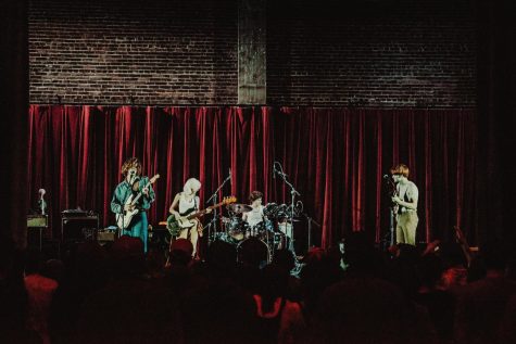 Common Koi band members perform in front of a red velvet curtain at the Whiteside Theater in Corvallis.