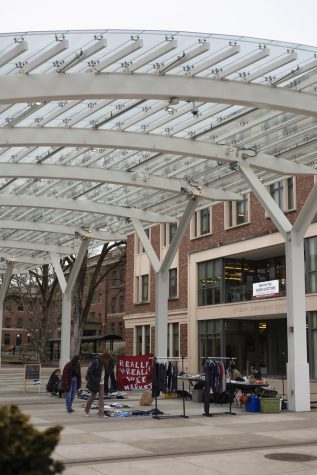 A wide shot of the Student Experience Center Plaza with the RRFM going. Several community members browse the market with the plaza awning overhead.