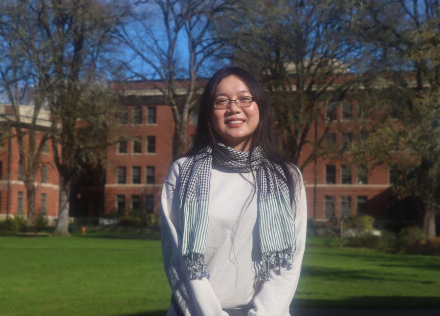 Karree Lee smiles for a photo in the Memorial Union quad on a sunny Sunday, March 20. Lee is wearing a sweater, glasses and a scarf.