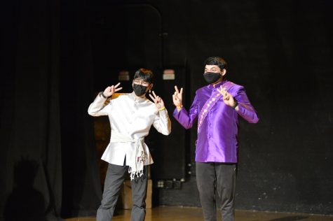 Tyler Strid, left, and Karthik Vijay stand together on stage while giving peace signs with their hands.