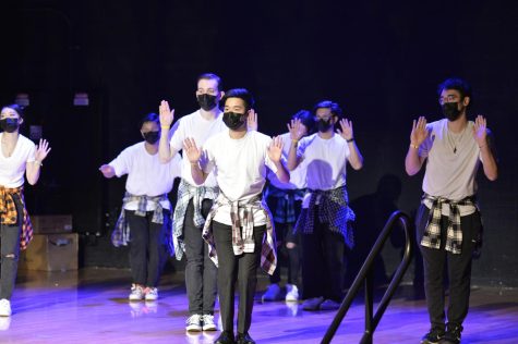 A group of students are dancing in sync on stage.