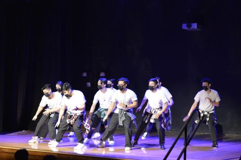 A group of students are dancing in sync on stage.