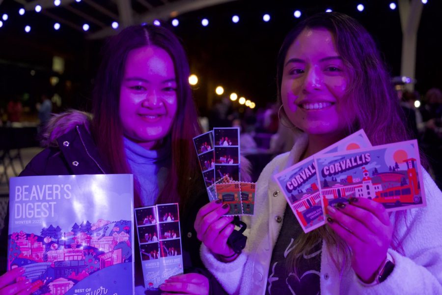 Madeline Judokusumo (left) and Jessica Garcia (right) smile with their photo booth strips, postcards and magazine.