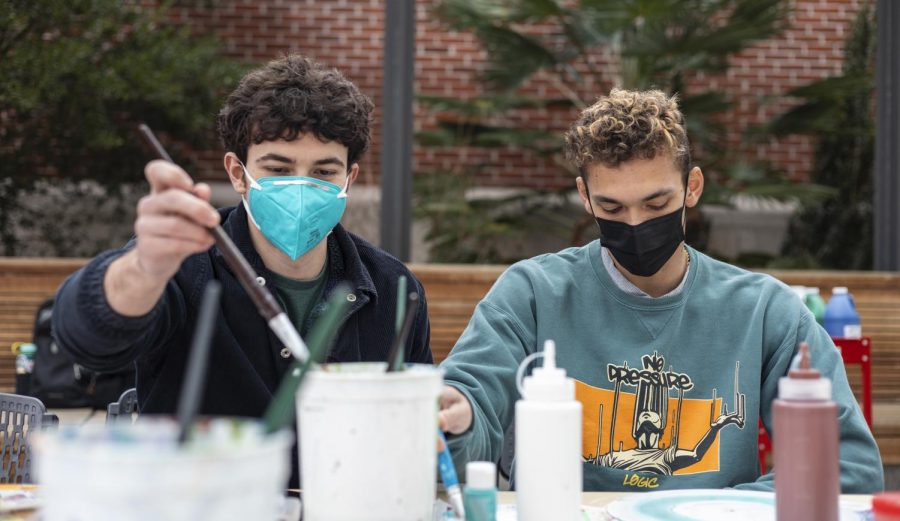 Gabriel Bendat, left, third-year environmental economics and policy student, and Joe Pittman, fourth-year mechanical engineering student, painting records together at the record painting event on Feb. 16, 2022 in the Student Experience Center Plaza.