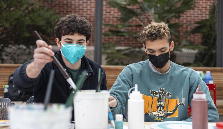 Gabriel Bendat, left, wears a corduroy button-up shacket, and Joe Pittman wears a Logic No Pressure album crewneck sweatshirt as they paint records.