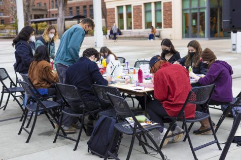 A group of students and KBVRfm organizers concentrate on their art all around the table.