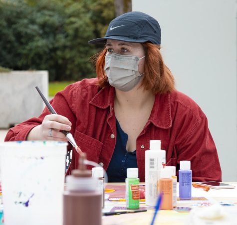 Jen Dirstine wears a jacket and Nike baseball cap as she paints a record.