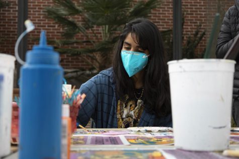 Leah Venkatesan wears a Queen band tee with a flannel over it as she paints a record.