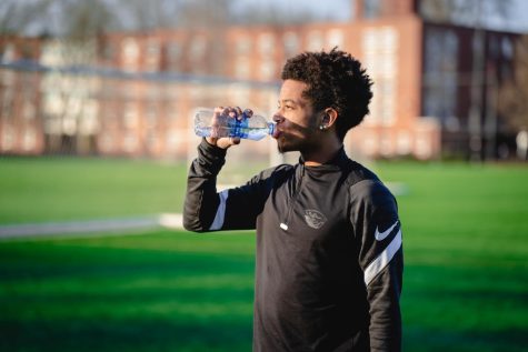 Dante Williams takes a drink out of a plastic, single-use water bottle while wearing an OSU Beavers shirt.