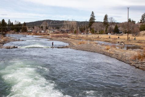 People hang out around the water—some fishing, some rafting, and other bike on the bike bath along the Deschutes River.
