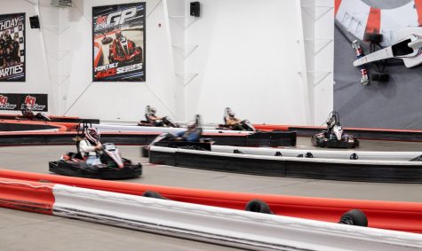 Several people in go karts maneuver through the course as the speed by.