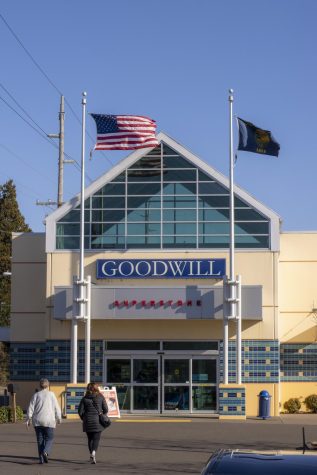 People walk into Goodwill Corvallis as an American flag and an Oregon flag wave overhead.