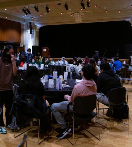 Attendees mingle amongst each other as they sit around tables.