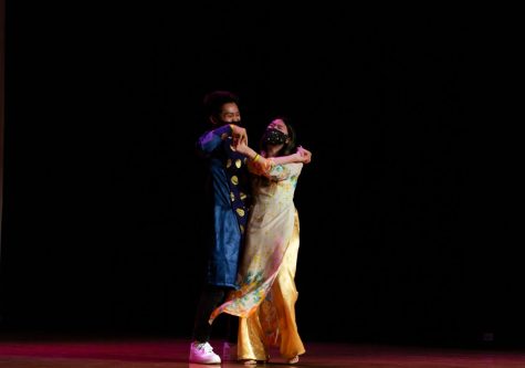 Two members of the fashion show laugh as they dance together on stage.