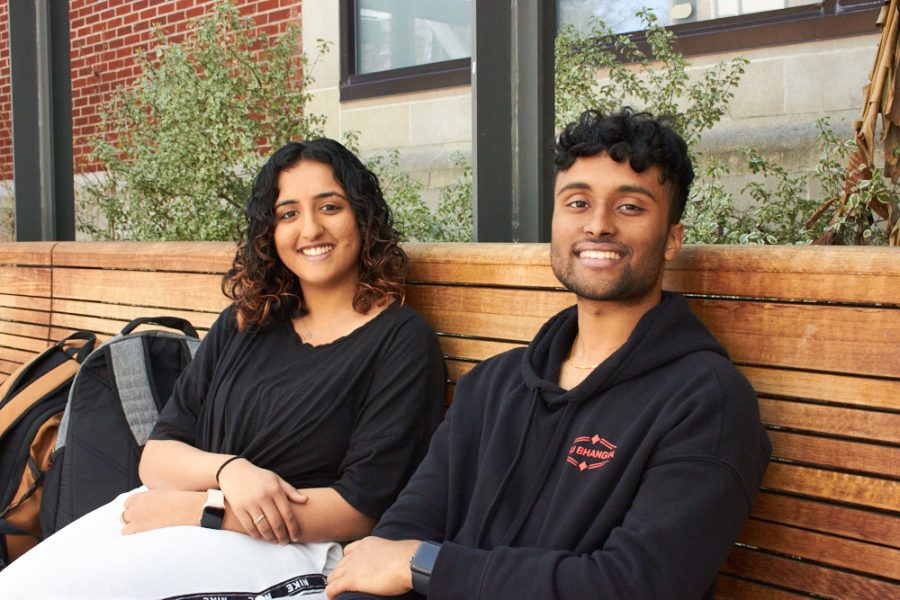 STudents Yesha Jhala and Rohan Bukka sit next to each other on a bench
