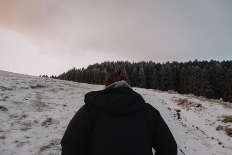 The photographs Meegan Sharp hiking up a snowy hill at sunrise from behind.