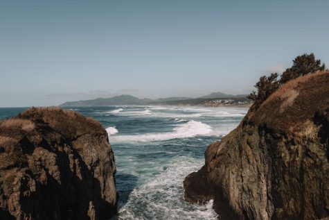 A view of the ocean crashing against two cliffs.