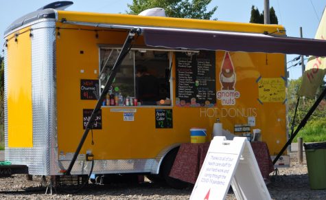 A volunteer works in the GnomeNuts food cart on a warm, sunny day.