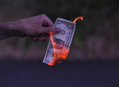 Pictured here is a dollar bill on fire outside of Graceland Church, in Corvallis Ore. Spending money when inflation is so high can feel like a complete waste of money, or like setting it on fire, since $1 does not buy much these days.