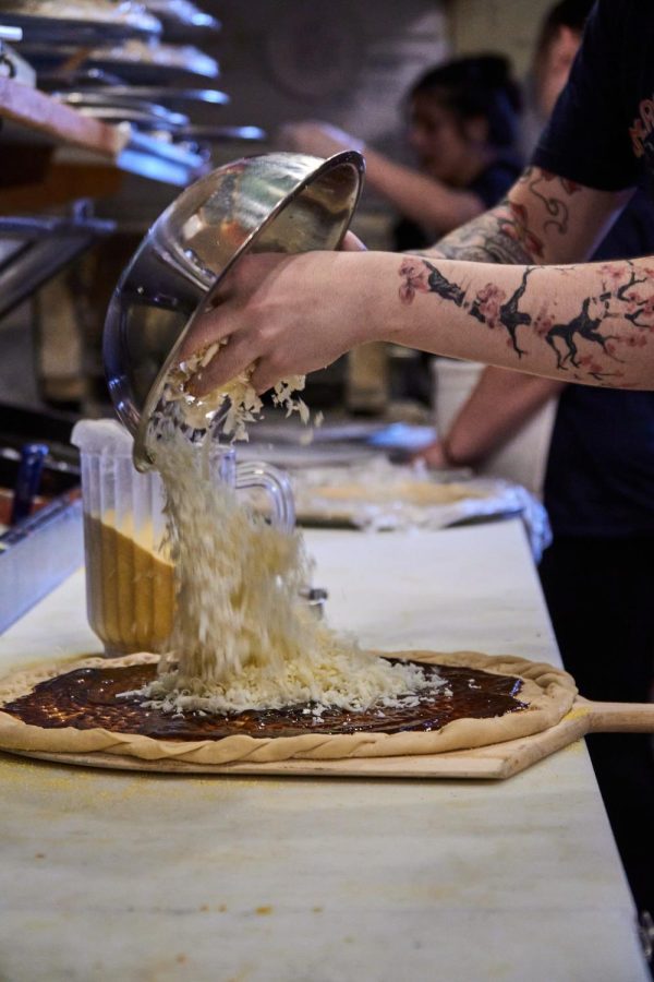 Kamron Fonger pours cheese onto a pizza at American Dream on Monroe Avenue.