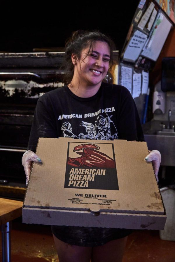 Abbey Bovee, employee, holds up an American Dream Pizza box at the restaurant on Monroe Avenue.