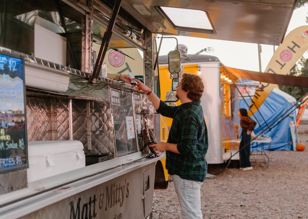 Cole Pearson (he/him) purchases food from Matt and Mitty’s food cart at the Melon Shack on October 5, 2023. Matt and Mitty’s was one of many food trucks stationed at the Melon Shack.
