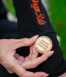 Jay VanDenBogaard, OSU Collegiate Recovery Program Coordinator, displays an OSU Collegiate Recovery Program sobriety chip.