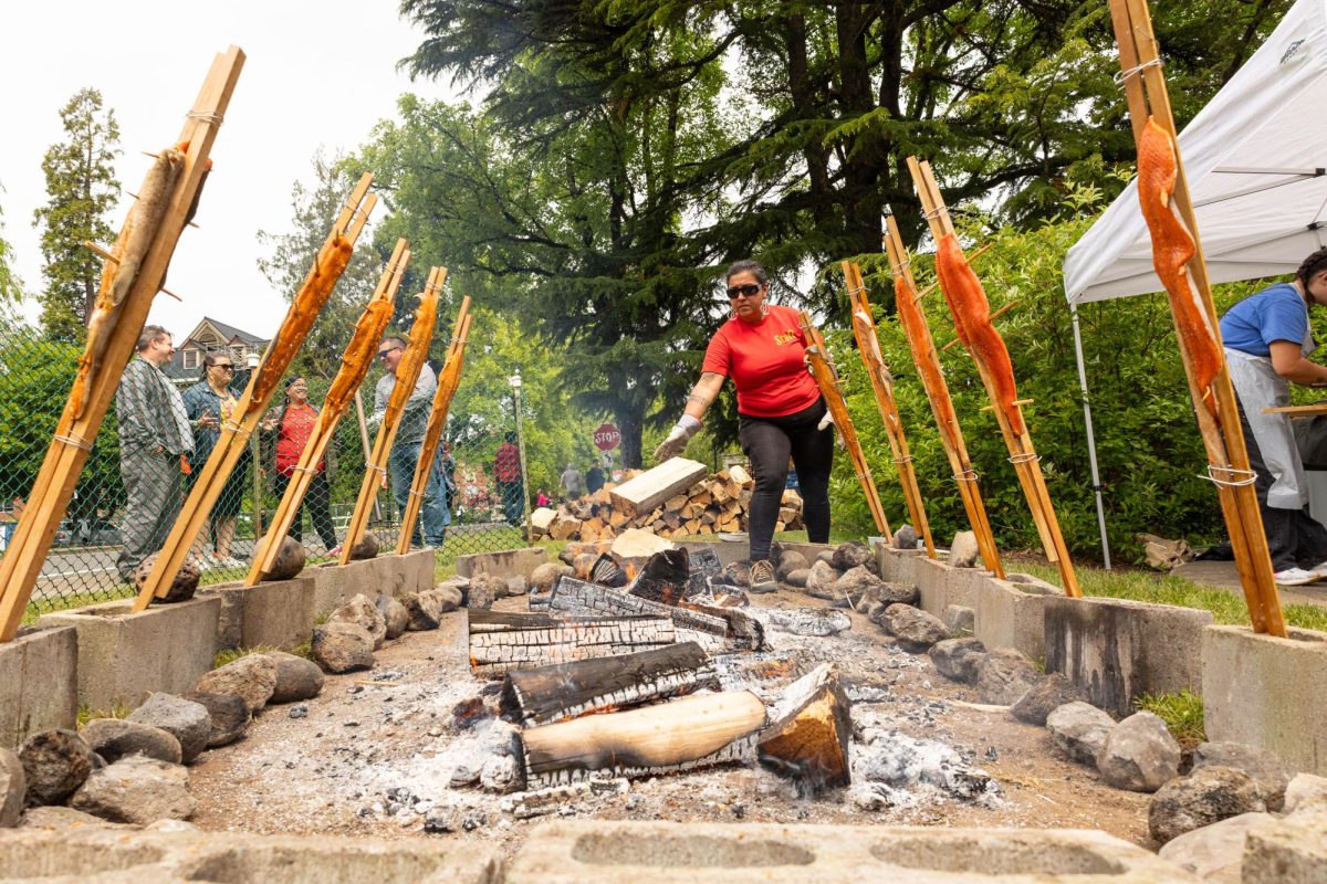 Luhui Whitebear adjusts fuels the fire cooking the salmon at the annual Salmon Bake, presented by kaku-ixt ina haws at OSU, in Corvallis, OR, on May 16, 2025.