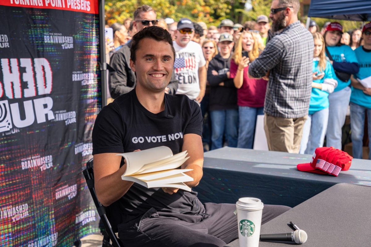 Charlie Kirk flips through “The Achievements of Kamala Harris” book from a debater at his “You’re Being Brainwashed” tour on Oct 11, 2024 at Oregon State University.